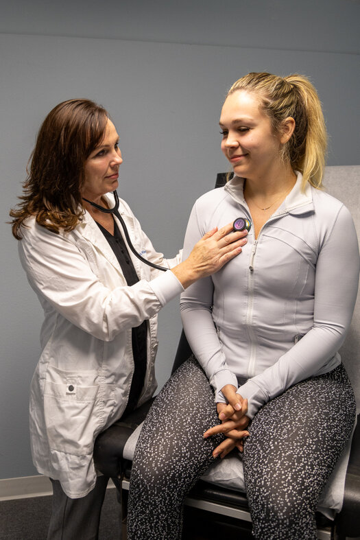 Photo of Nurse Practitioner Amanda Mendoza using a stethoscope to examine a patient